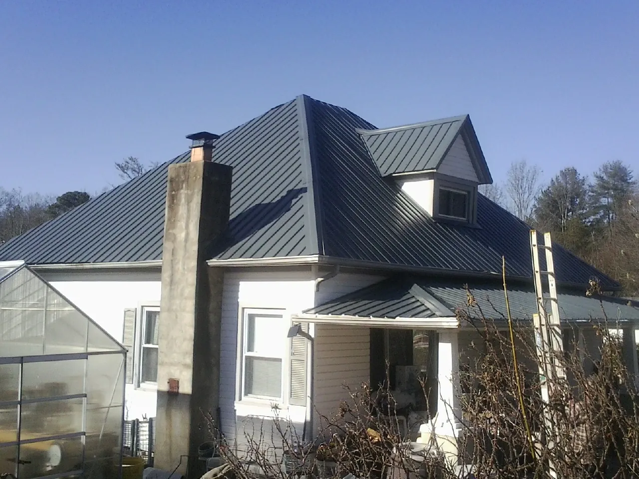 Dark blue standing seam metal roof on a white farmhouse with dormer — Slate & Tile Roof Repair by Roofing Brothers in Merino