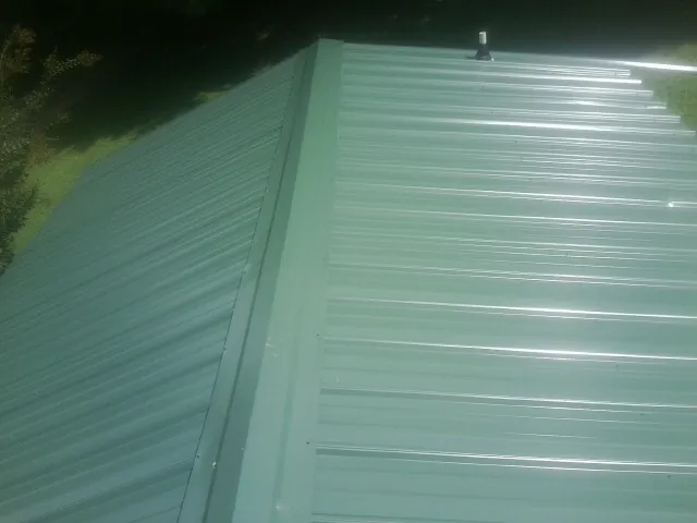 New green metal panels meeting at the ridge of a roof — Flat Roof Repair work by our crew in Merino