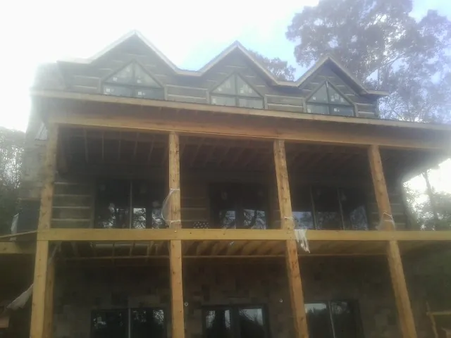 Dormers and porch framing on a large log home under construction — Roof Coating work by our crew in Merino