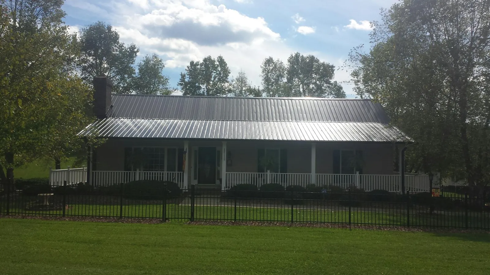Gray metal roof on a brick ranch with a full width front porch — Gutter Guard Installation work by our crew in Merino