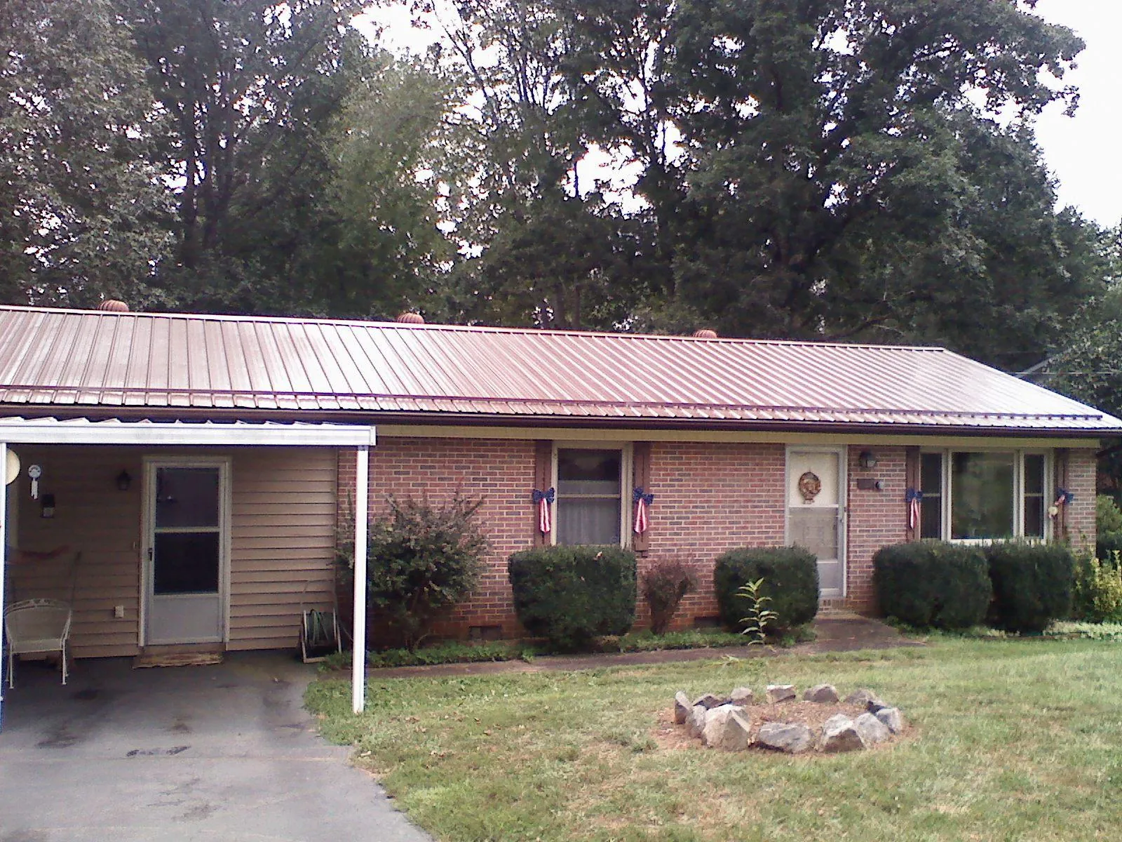 Bronze metal roof and carport on a brick ranch home — Roof Repair work by our crew in Merino