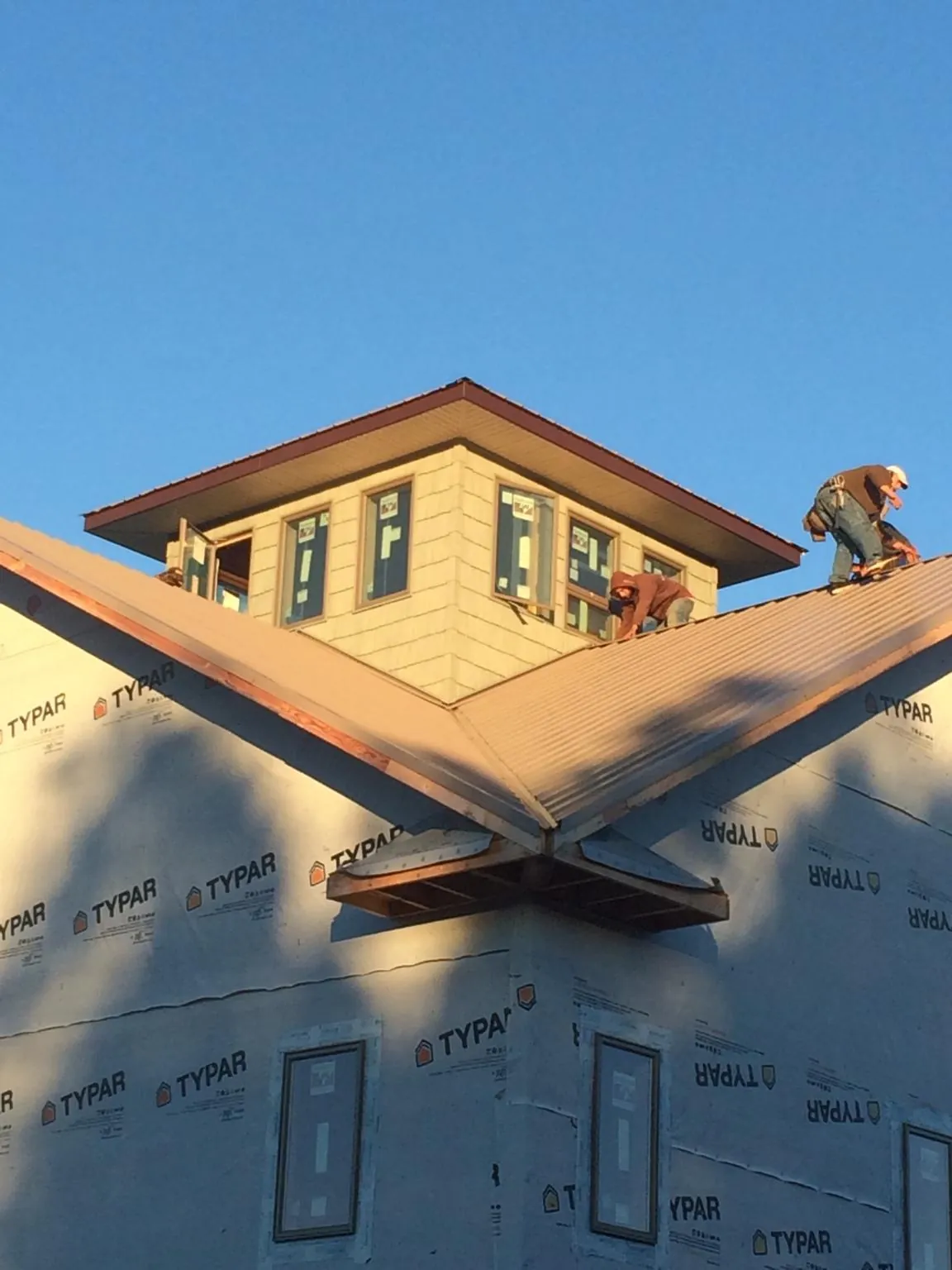 Roofers working around a rooftop cupola on a new metal roof at sunset — Roof Waterproofing in Merino by Roofing Brothers